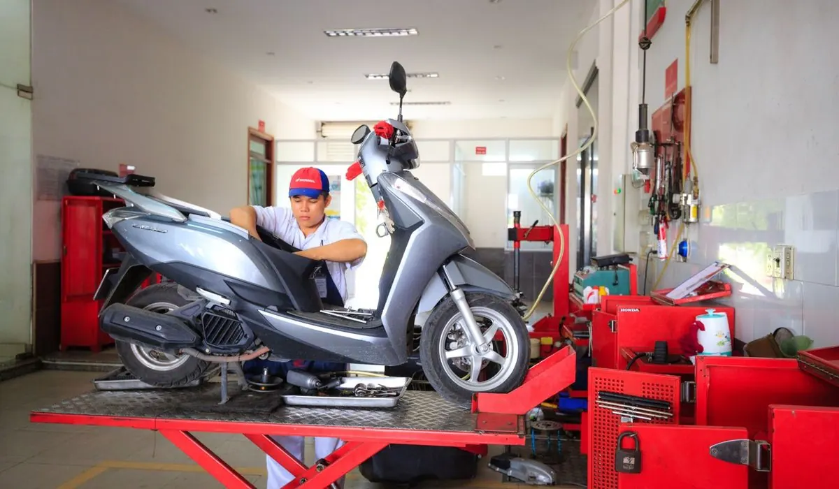 Mécanicien qui entretient un scooter dans un atelier