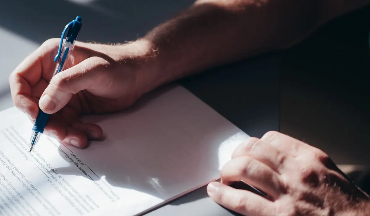 Main qui remplit un formulaire administratif au stylo bleu