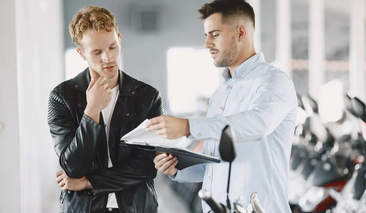 Deux hommes qui lisent un document dans une concession moto