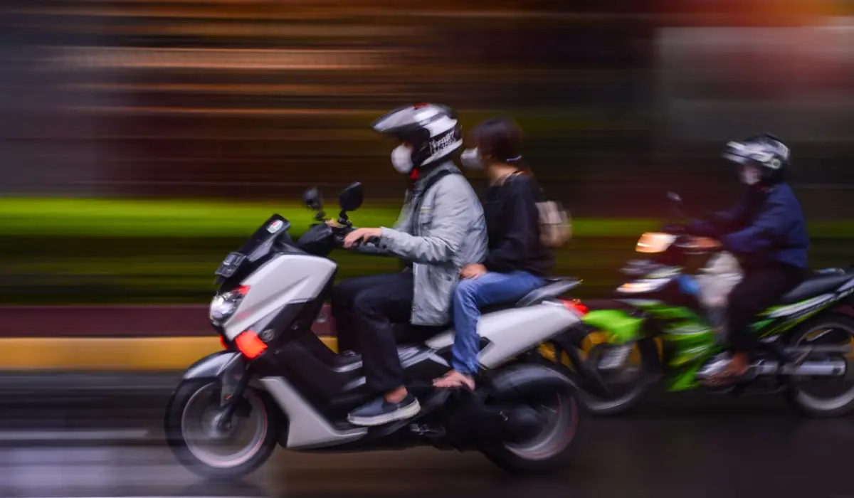 Deux scooters 125 dans la circulation, pilote et passager casqués